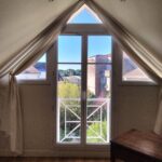 Bright student bedroom with large windows overlooking a peaceful garden in a welcoming host family home in Bordeaux.